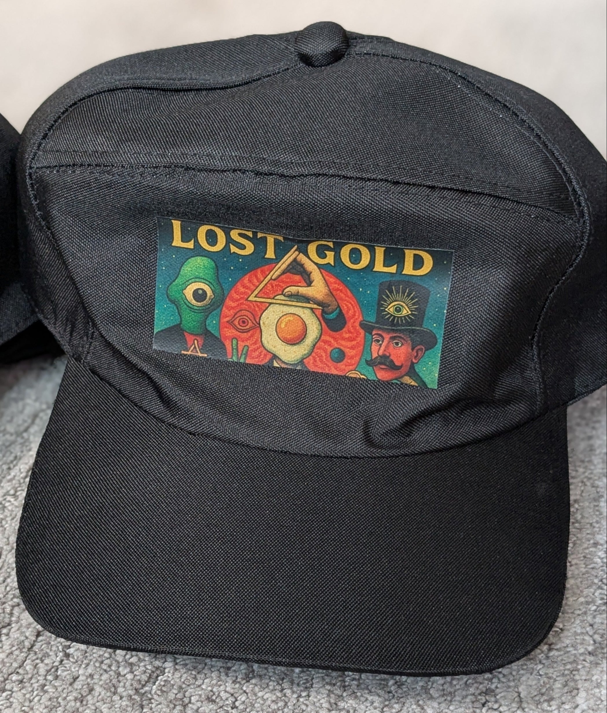 Black cap with 'Lost Gold' logo on a gray surface