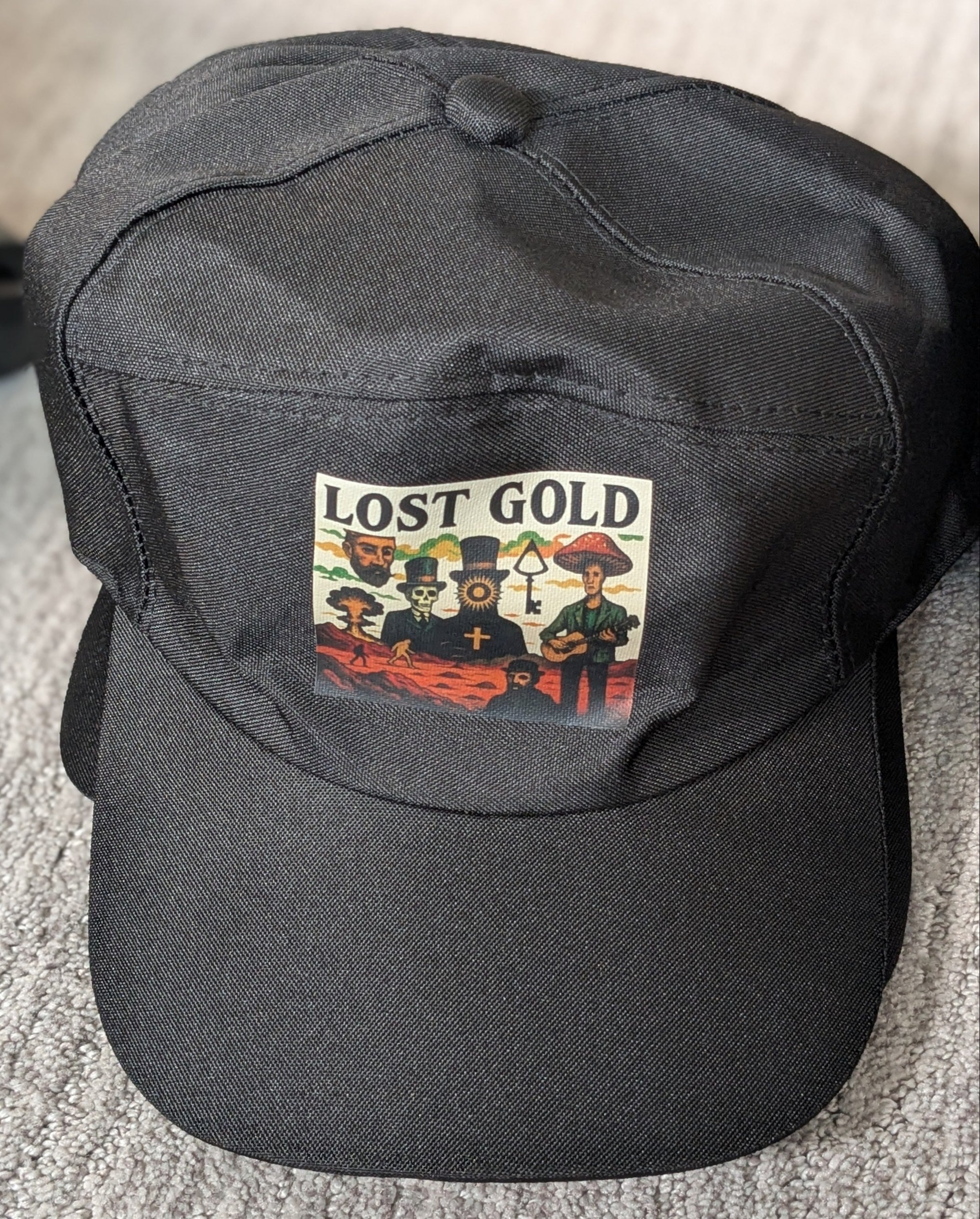 Black cap with 'Lost Gold' logo on a textured surface